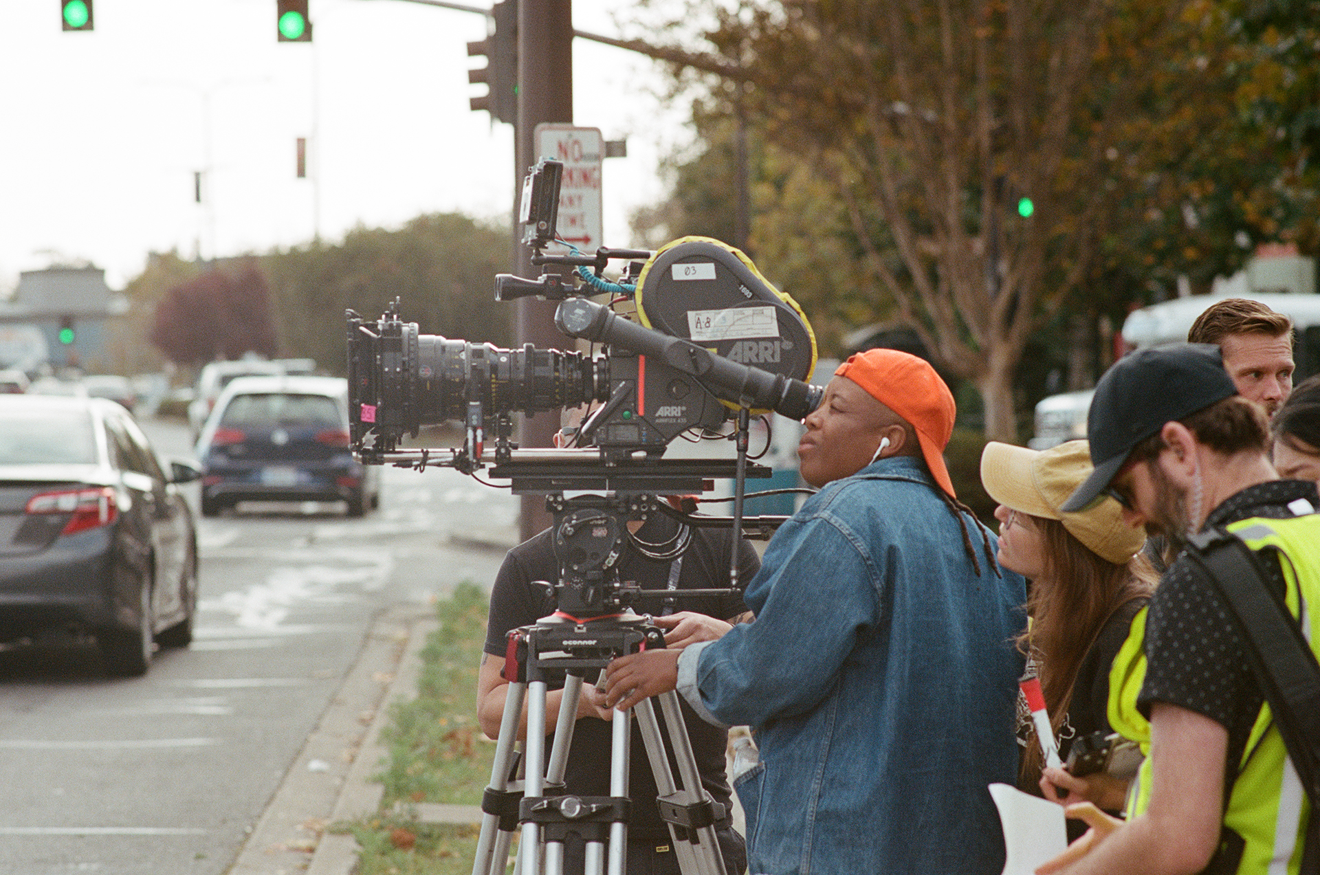 A director looks into a camera facing an Oakland street, with a film crew behind them.