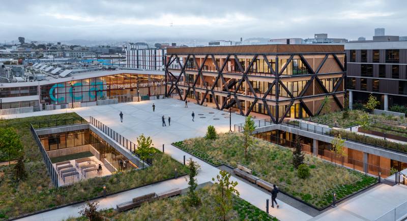 aerial view of large plaza, new building and old warehouse with foggy SF skyline behind