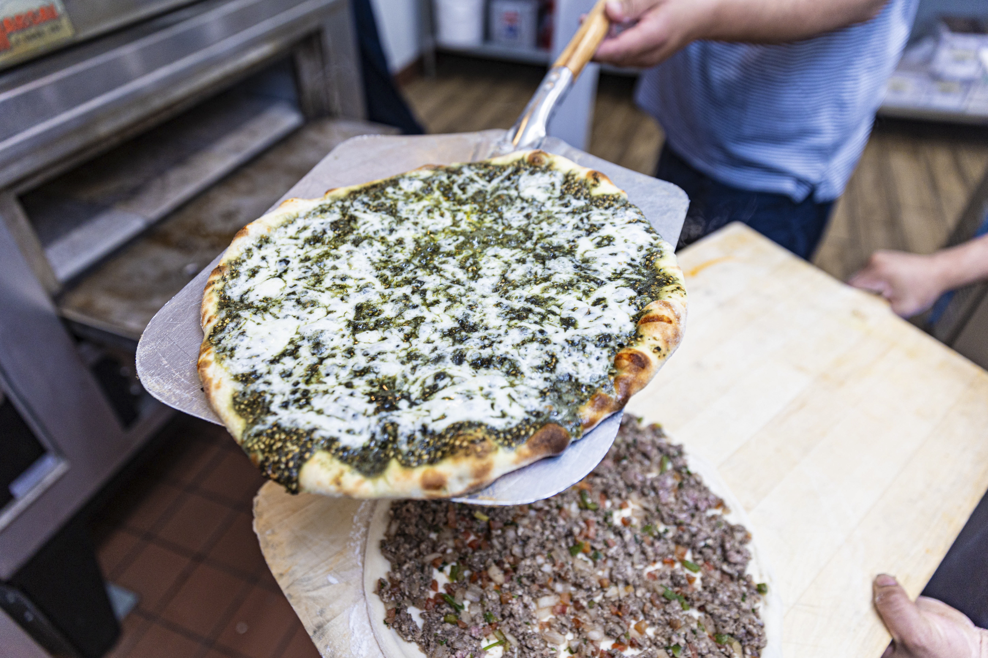 A cheesy za'atar flatbread on a pizza peel.