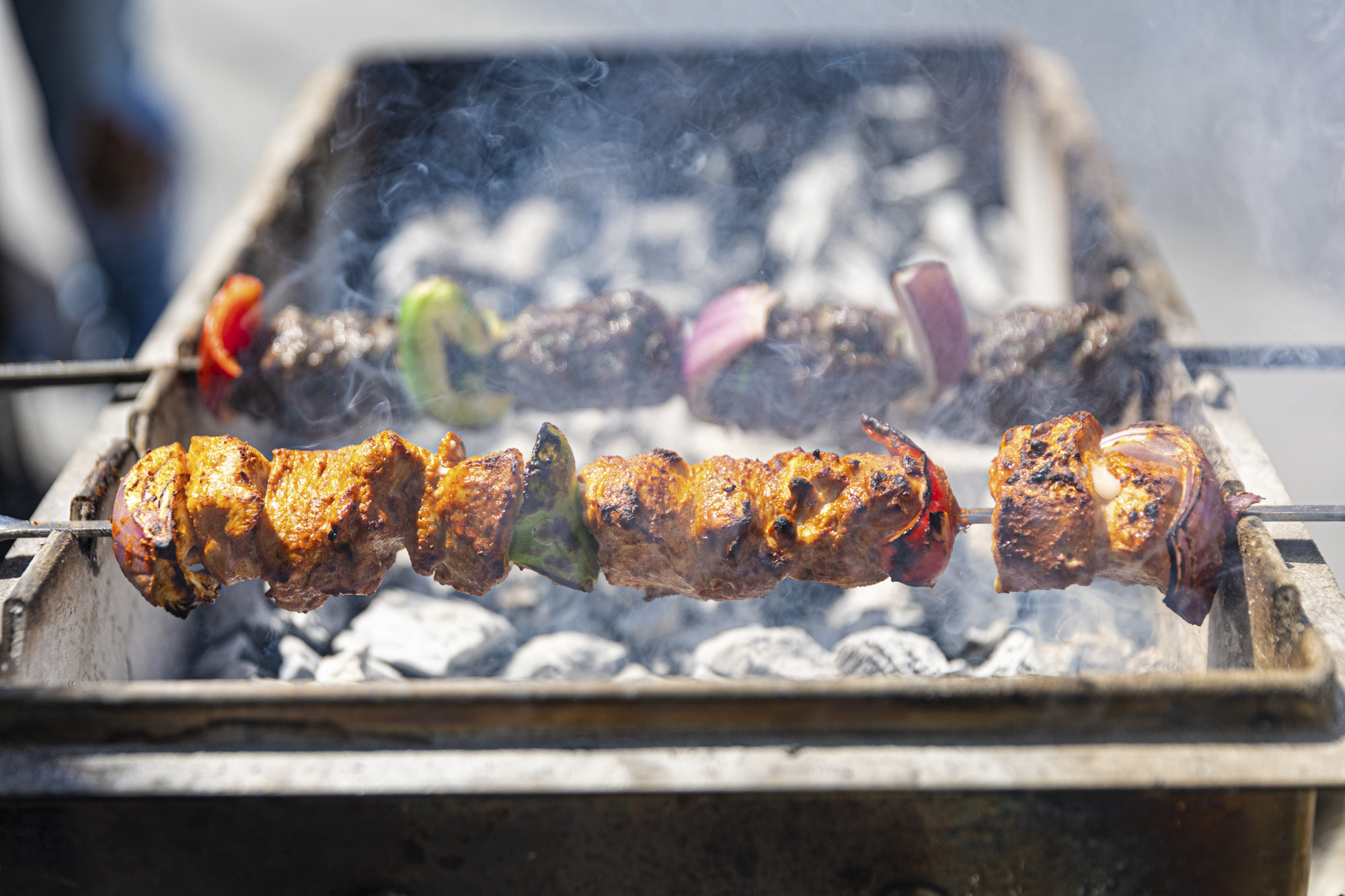 Kebabs cooking over a smoky charcoal grill.