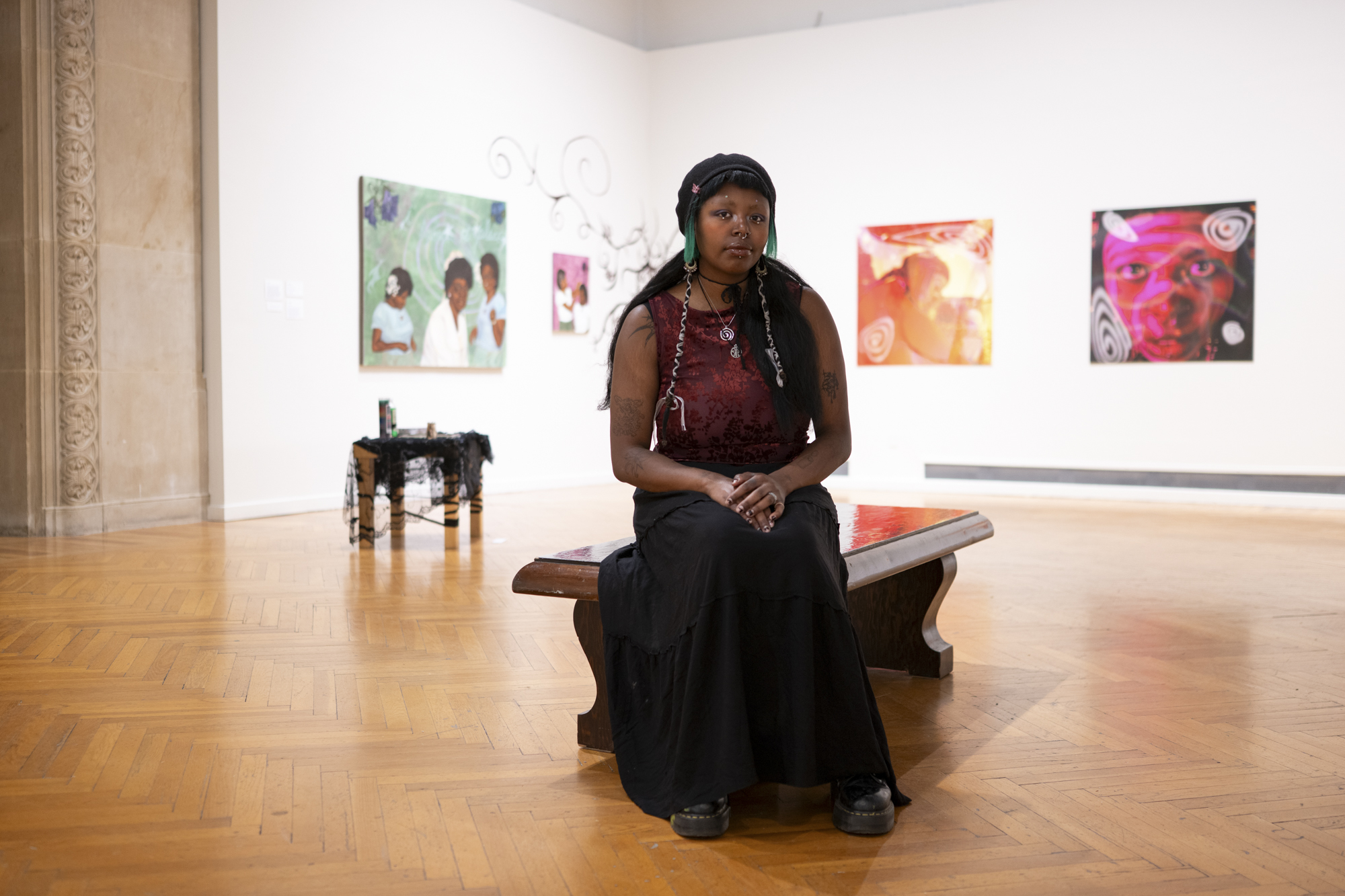 person sits on bench in gallery with paintings behind