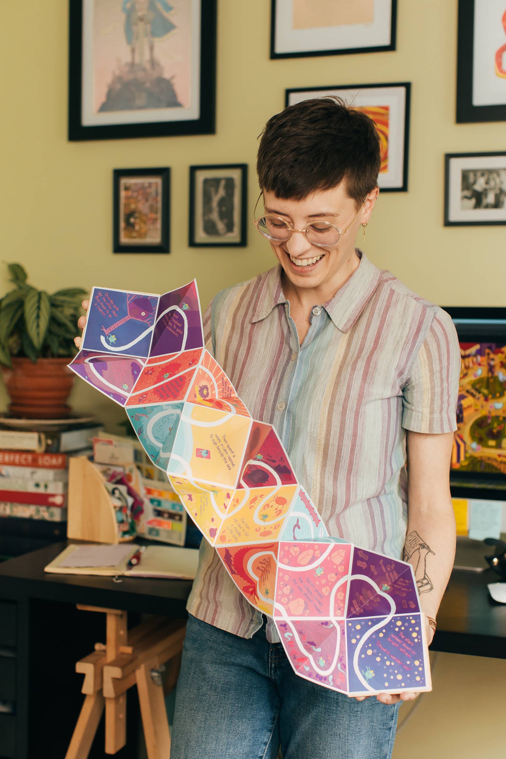 Portrait of a comics artist holding up a fold-out comic book.