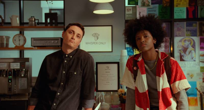 An artist and a coffee shop barista look into the distance in a film still.