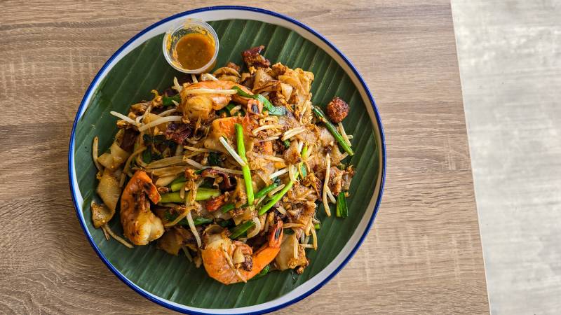 A plate of stir-fried rice noodles on a banana leaf–lined plate.