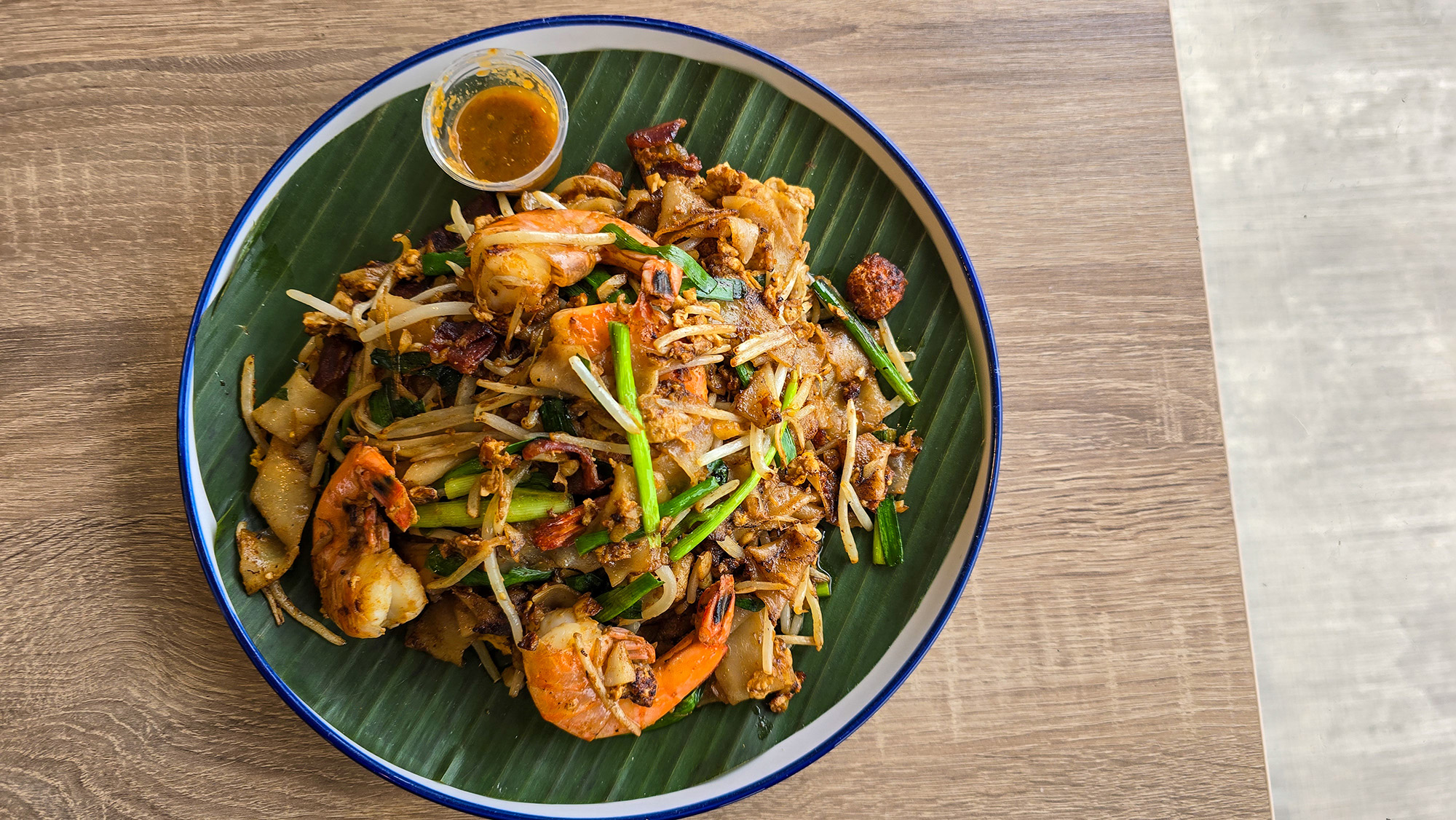 A plate of stir-fried rice noodles on a banana leaf–lined plate.