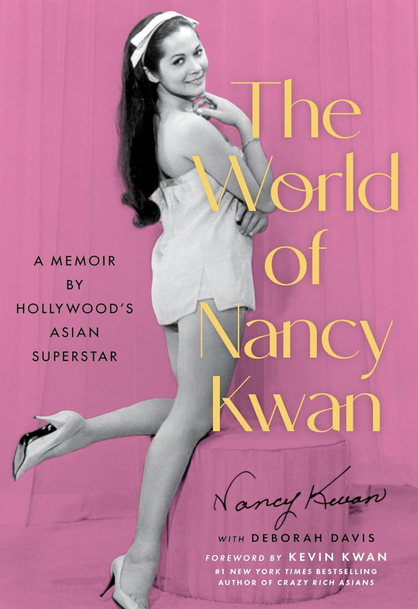 A pink book cover featuring a black and white photo of a beautiful Eurasian woman standing pin-up style with one leg cocked back, looking over her shoulder seductively. She is wearing a small white negligee.