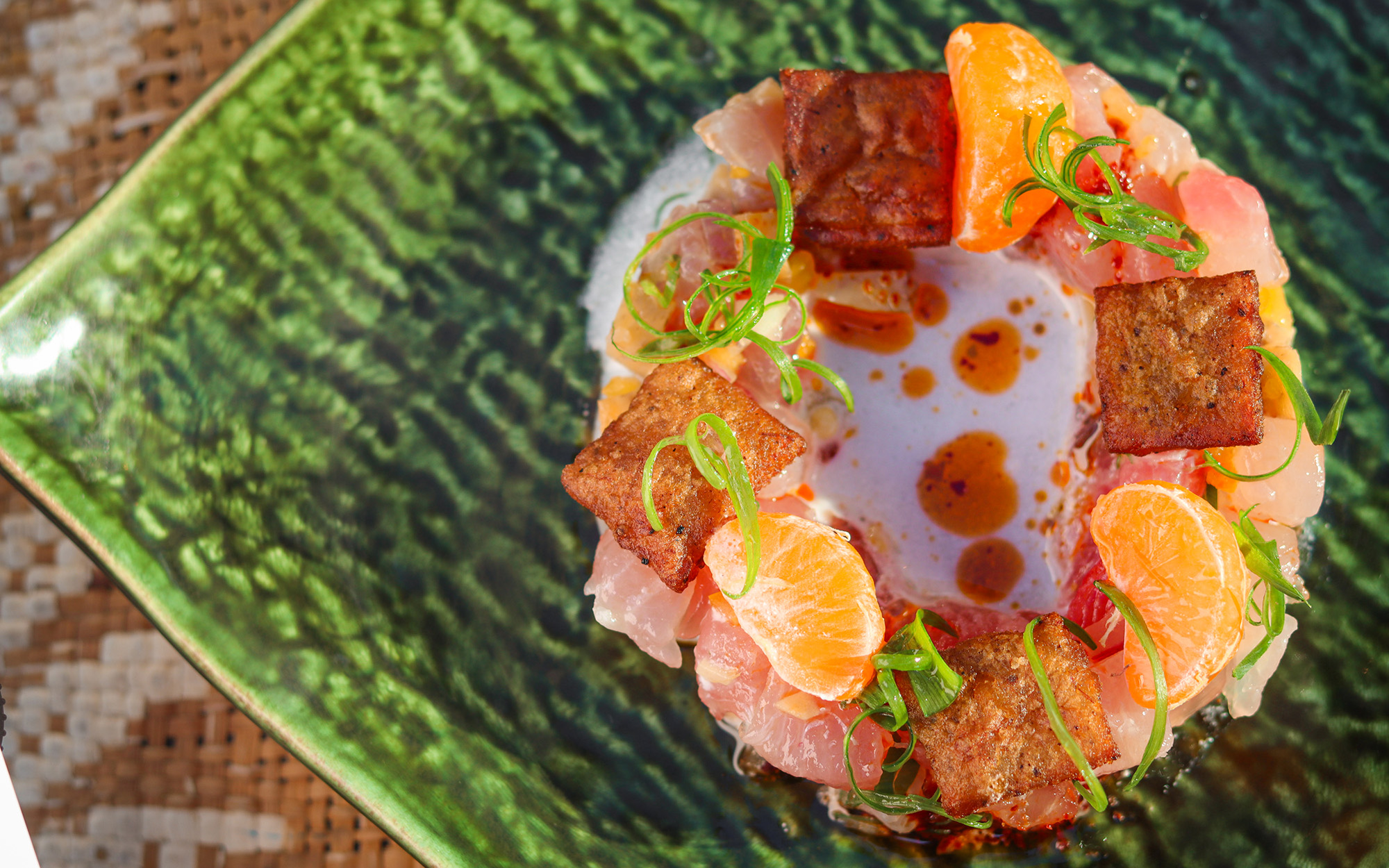Intricately plated raw tuna dish topped with slices of satsuma orange and plantain crisps.