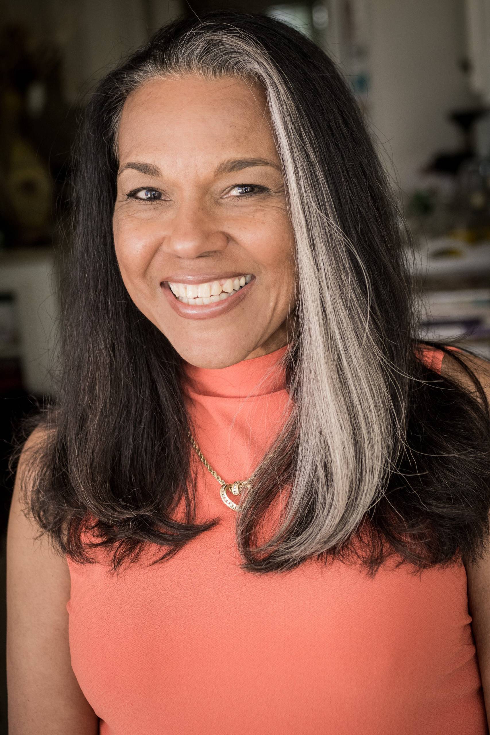 Woman in coral-colored top poses for author headshot.