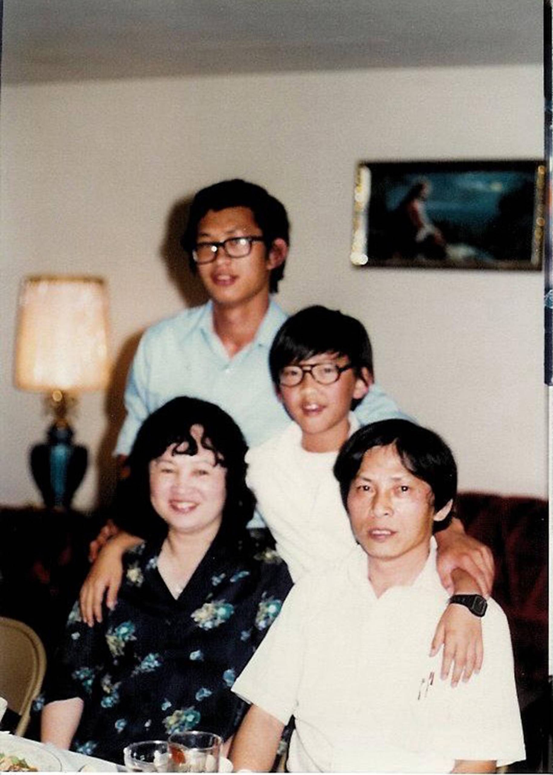 Photo of an Asian family — mother, father, and two sons — posing for a portrait.