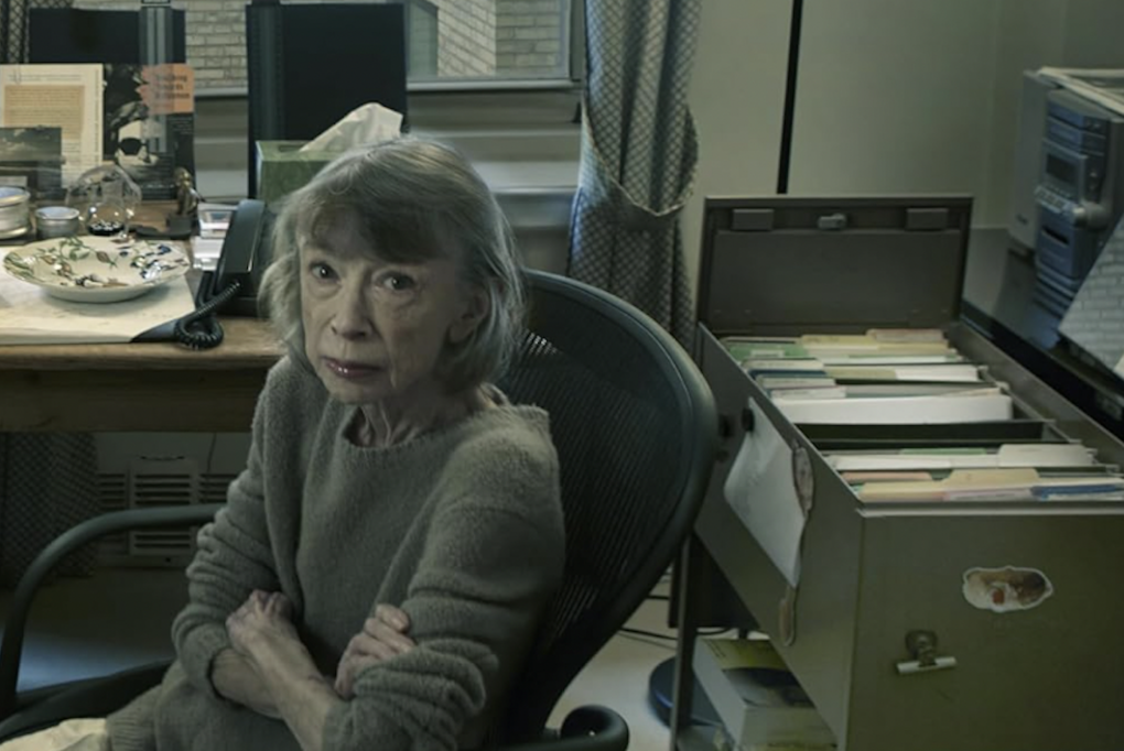 A book cover featuring a photograph of an older woman wearing a wool sweater, sitting at an office desk with her arms folded, an impervious look on her face.