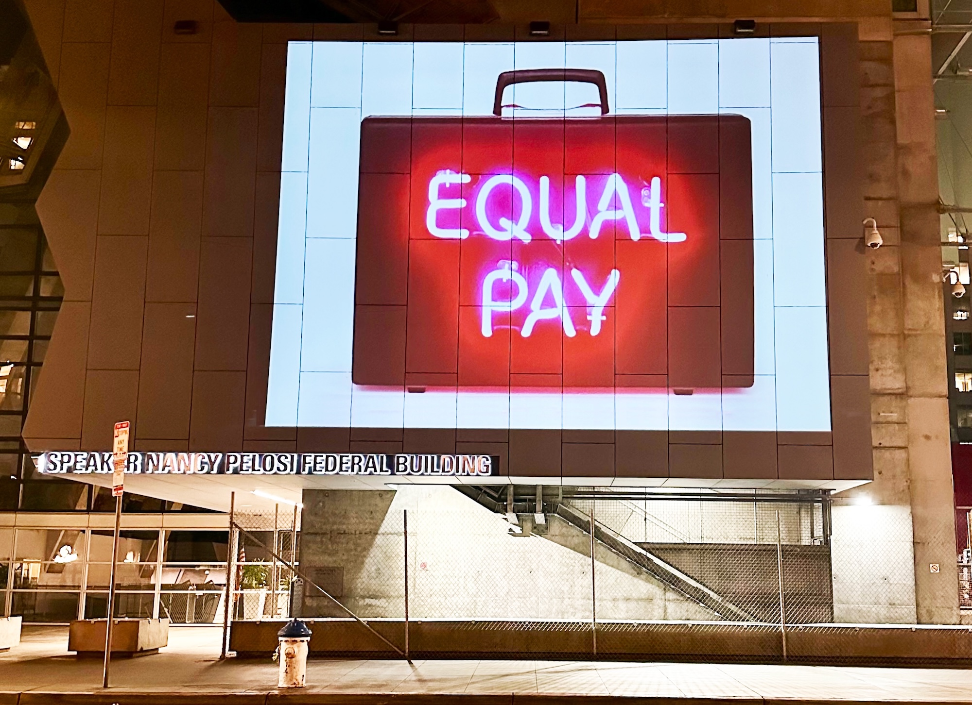 A large projection on the side of San Francisco's federal building showing a briefcase with the words 'Equal Pay' on it.