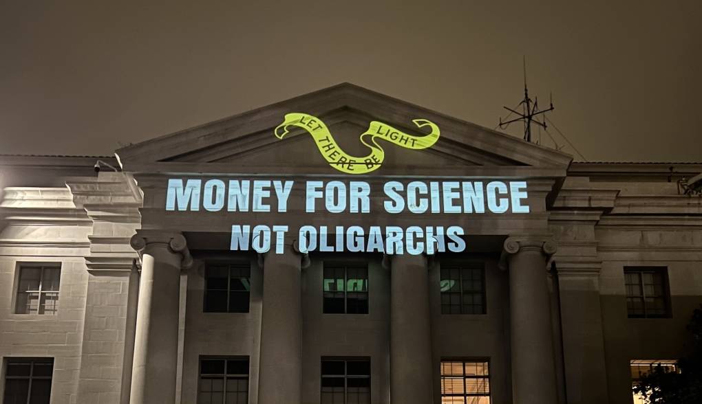 A projection reading ‘Money for science, not oligarchs’ on a building at UC Berkeley.