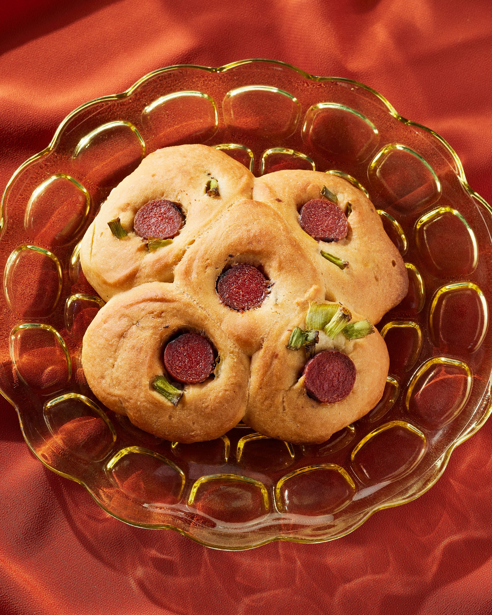 Taiwanese-style hot dog bun on a plate, against a red backdrop.