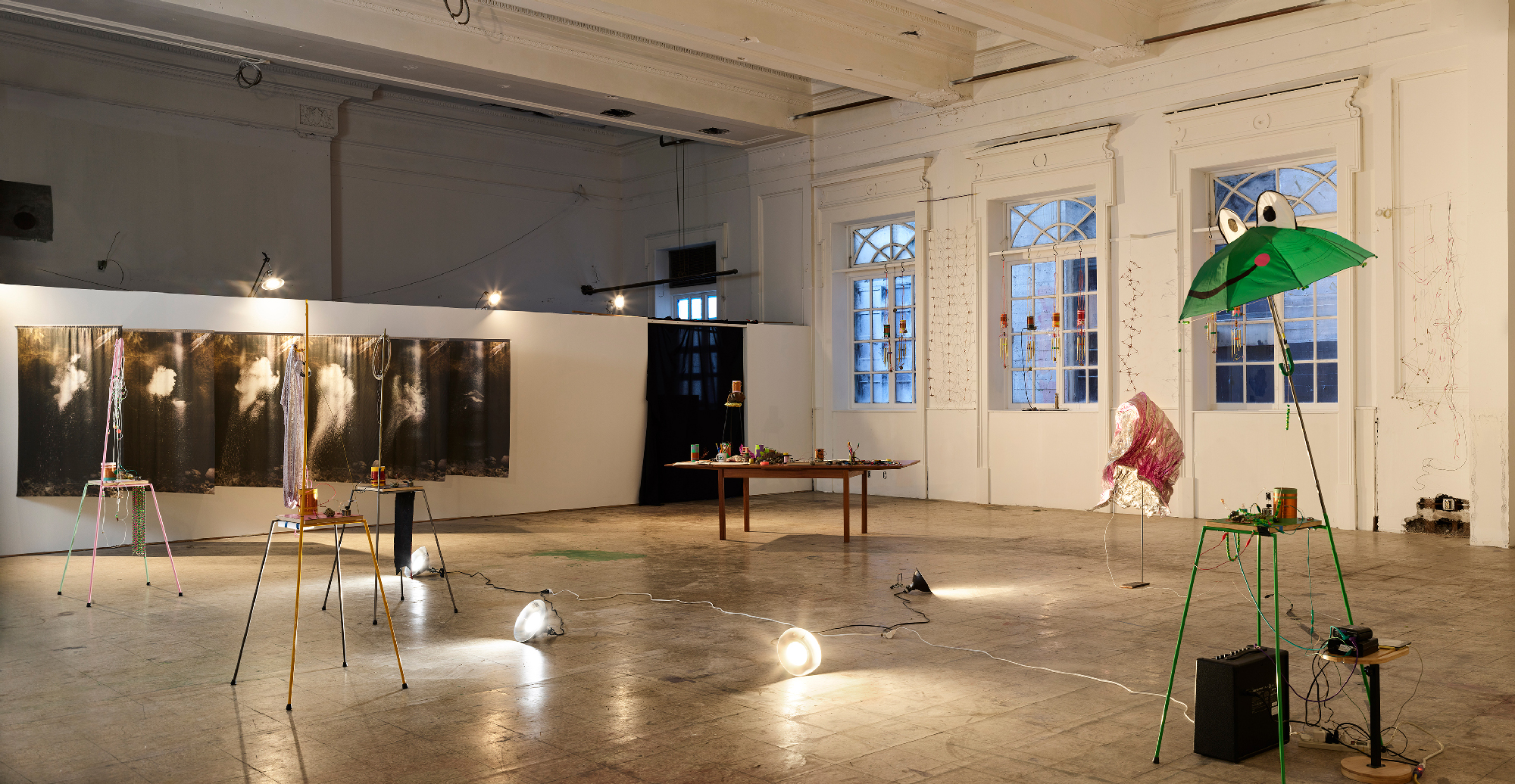 gallery space with tables and sculptures, lights on floor