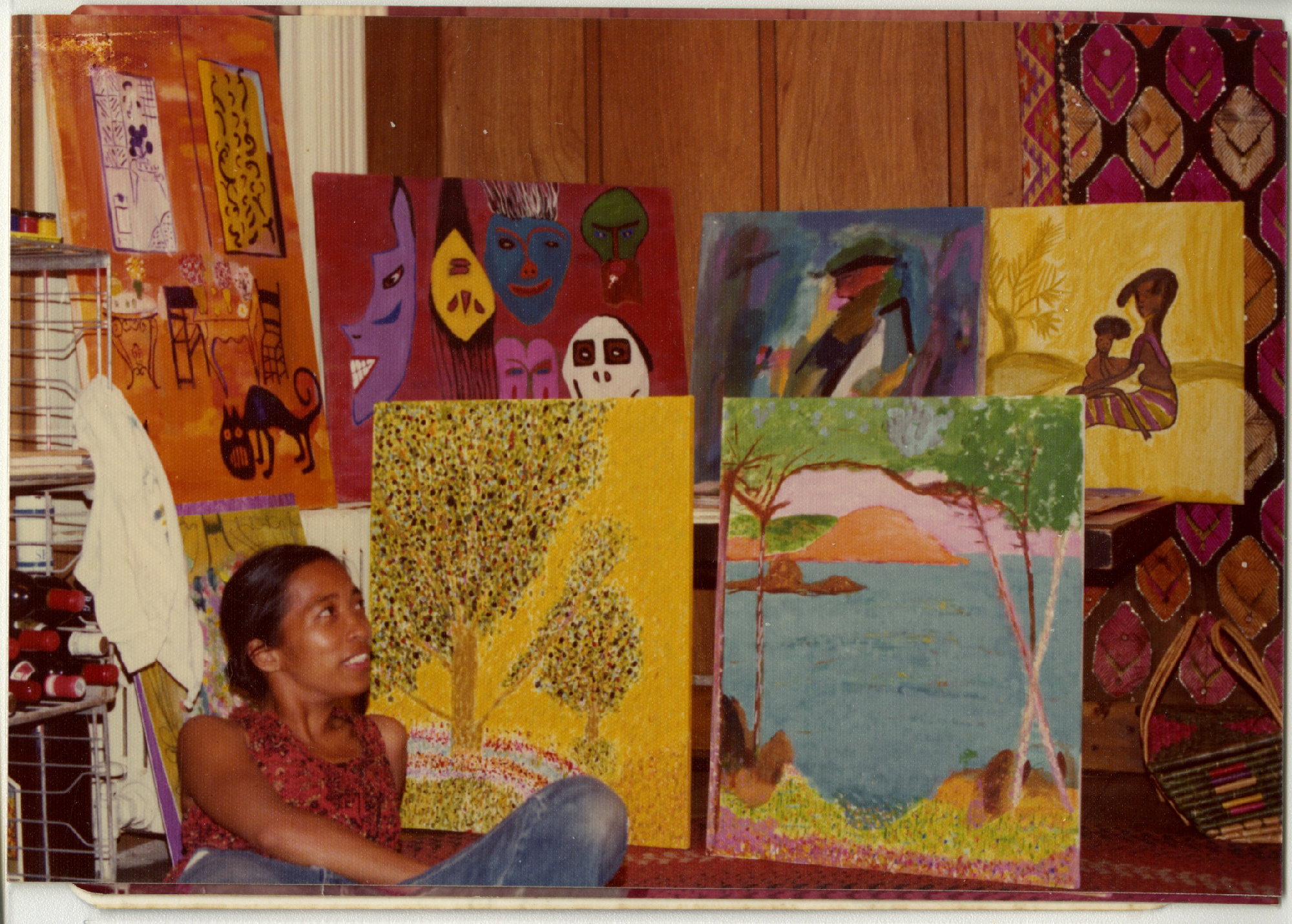 woman leaning back looks up at arrangement of paintings behind her