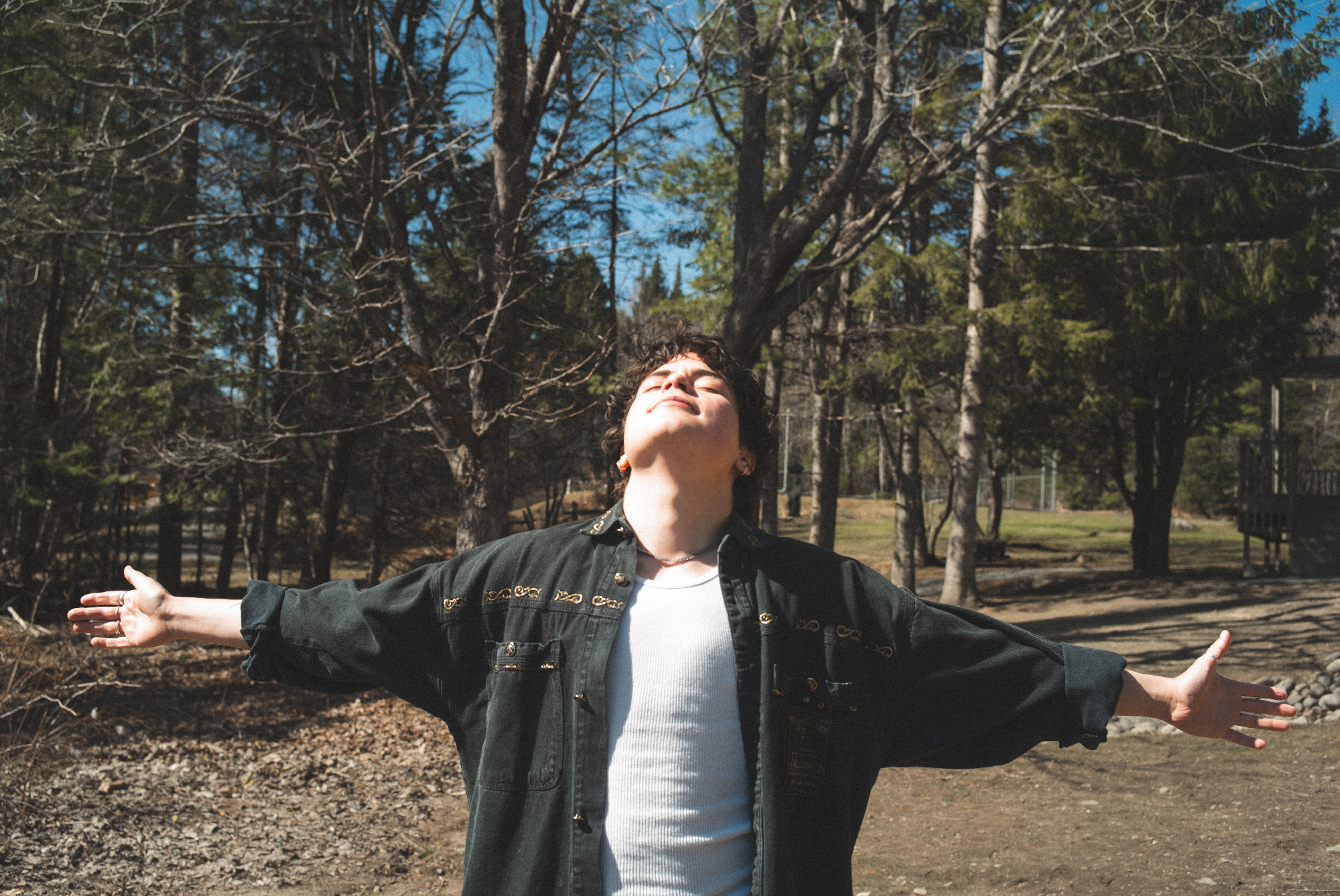 person with arms spread wide, head tipped back eyes closed to sun