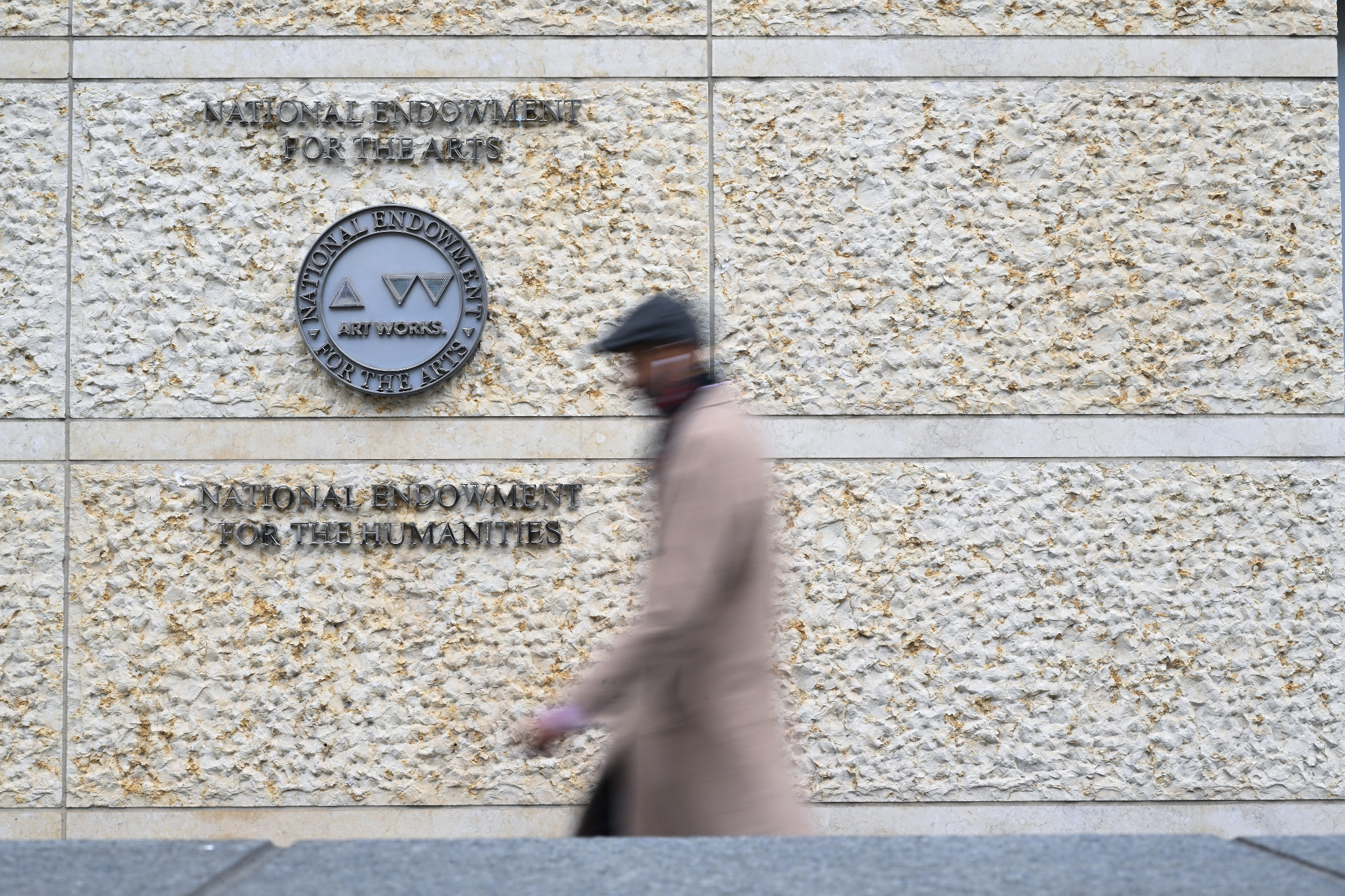 blurry figure crossing in front of building with agency names