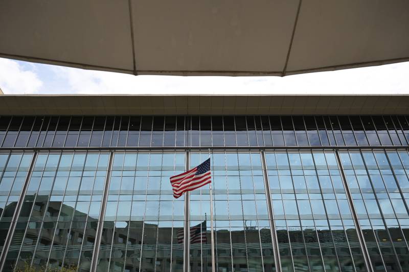 American flag flying between two buildings, slim view of sky