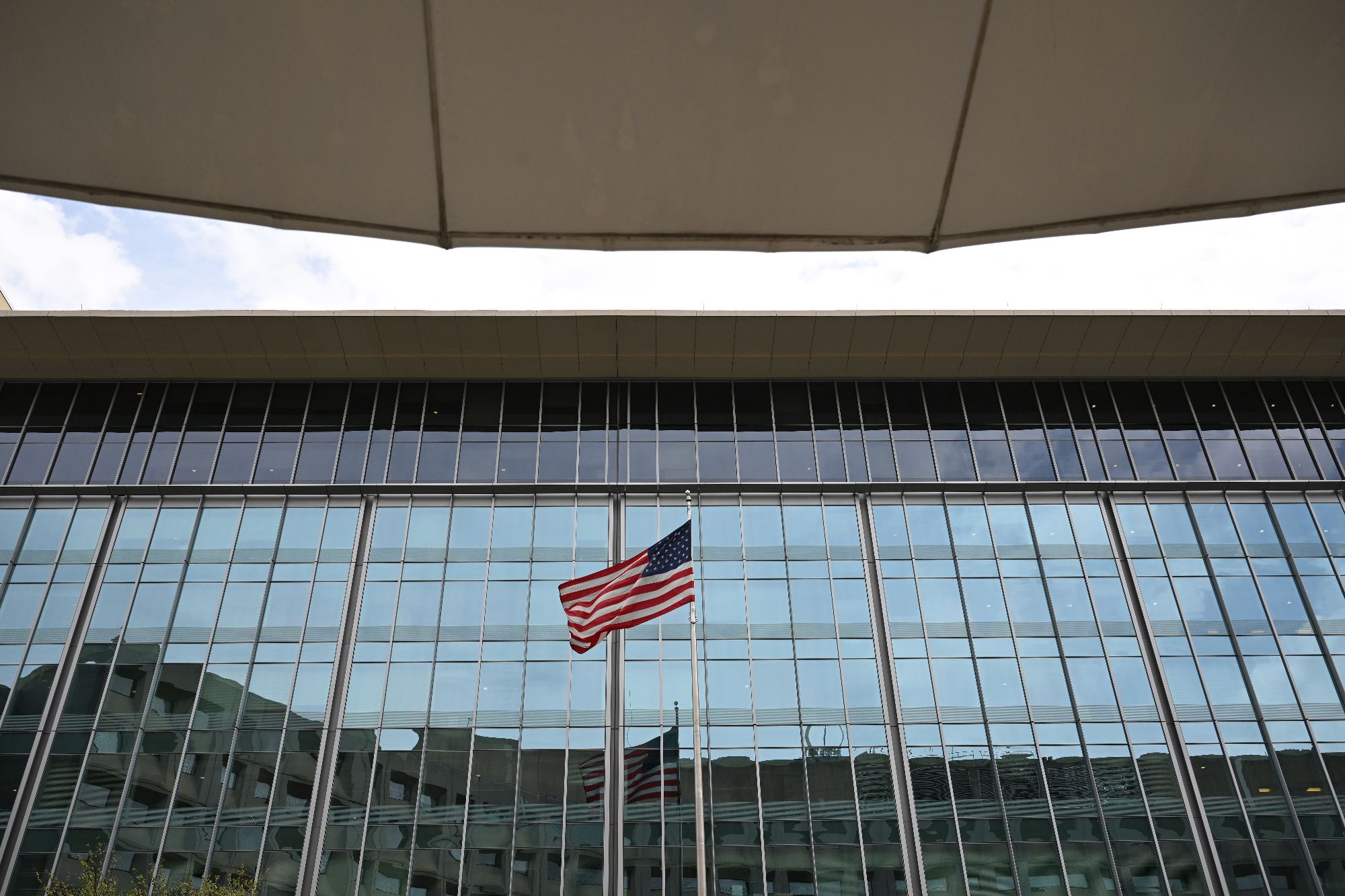 American flag flying between two buildings, slim view of sky