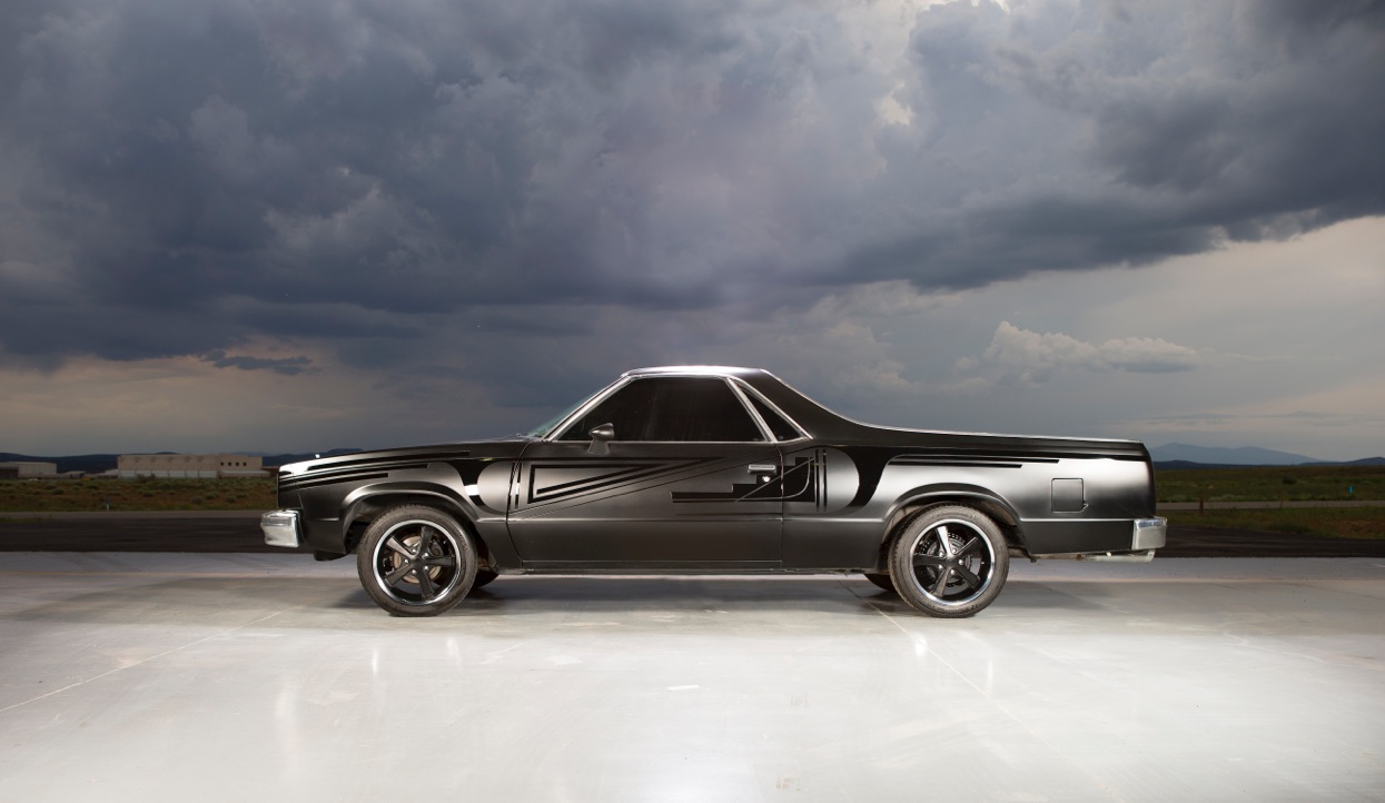 car against dramatic sky with matte and gloss black patterns in paint job