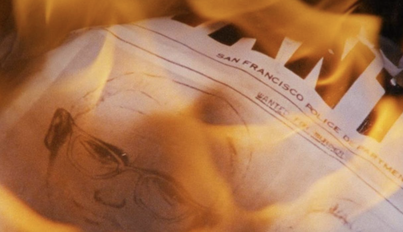 A piece of paper marked 'San Francisco police department,' featuring a sketch of the Zodiac Killer, burns in bright orange flames.