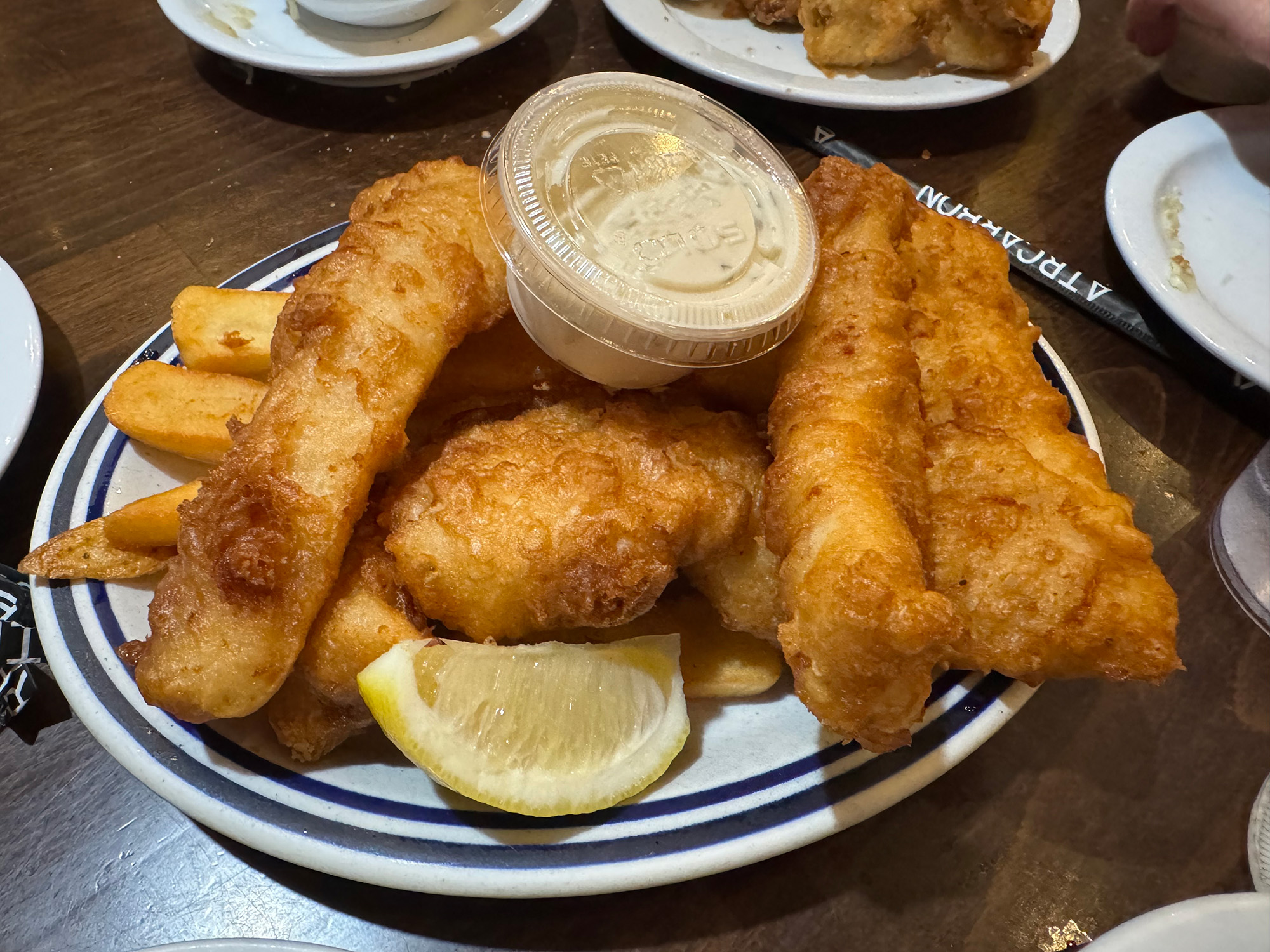 Fish and chips on a plate with a lemon wedge.