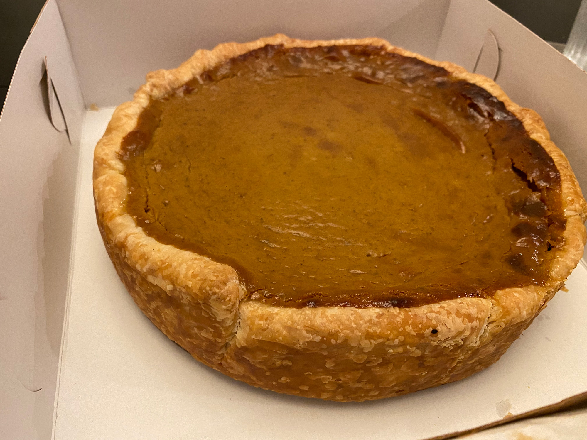 Whole deep-dish style pumpkin pie in the box.