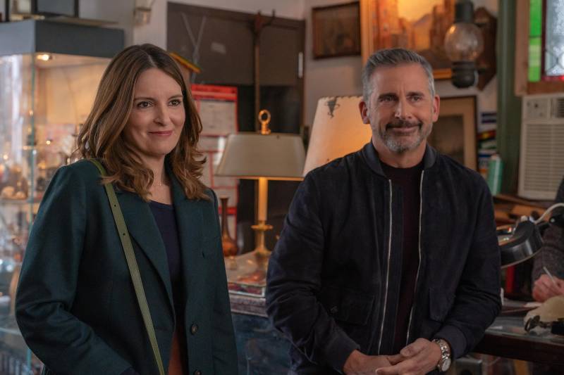 A middle aged white woman and white man stand politely smiling in an antiques store.