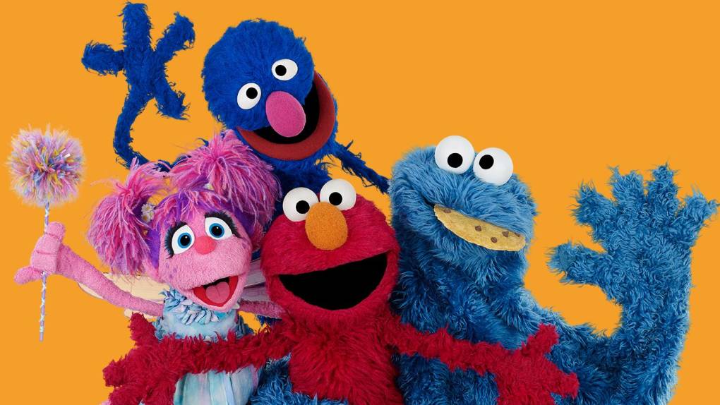 Four Sesame Street puppets waving: Abby, Elmo, Cookie Monster and Grover.