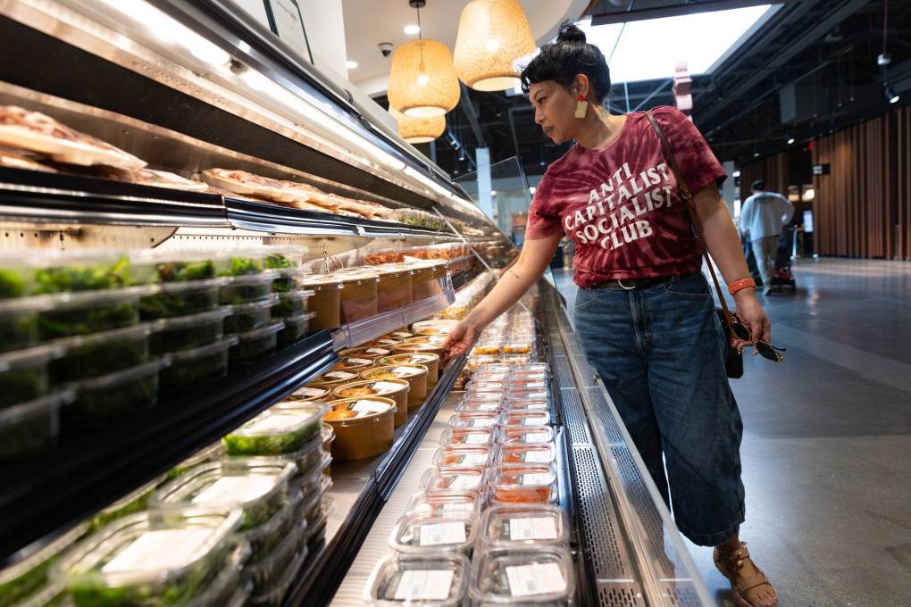 A woman browses a refrigerated display case at a high-end Asian grocery store.