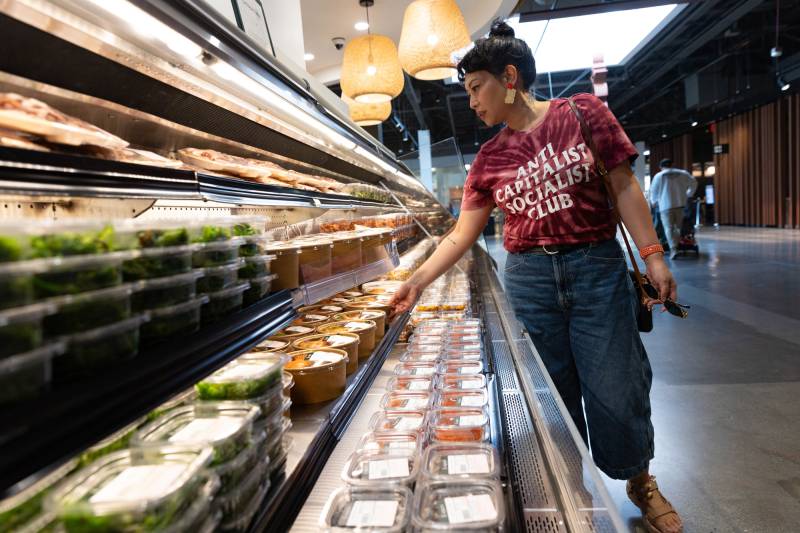 A woman browses a refrigerated display case at a high-end Asian grocery store.