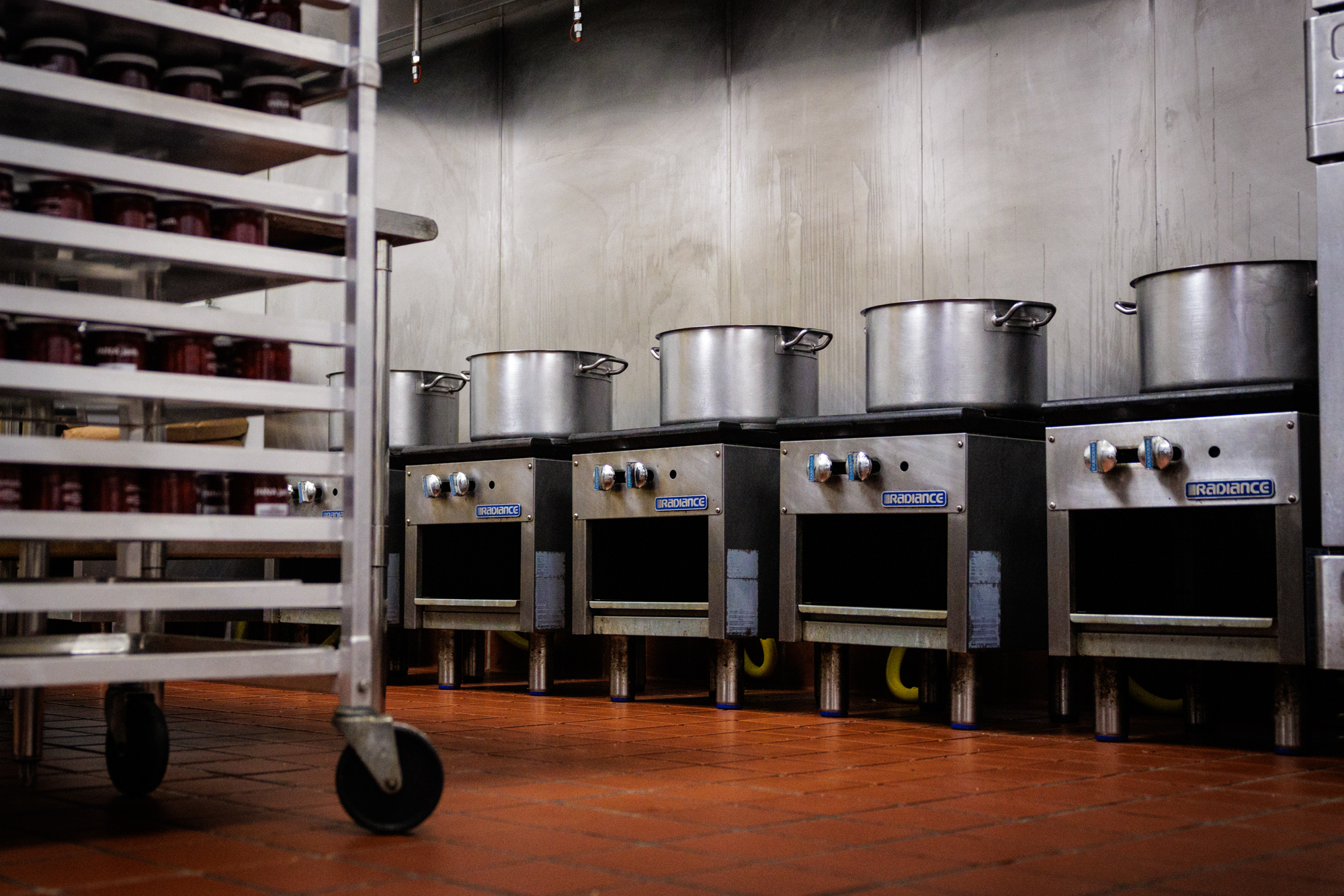 Big pots on a row of stovetops in a commercial kitchen.