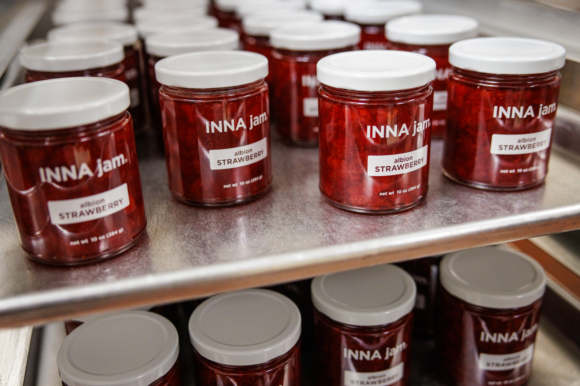 Jars of Albion strawberry jam on a shelf.