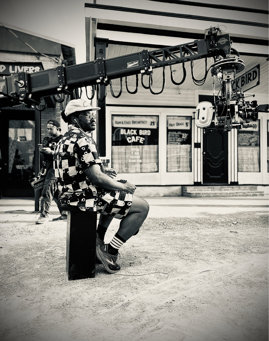 black-and-white photograph of Black man in print shirt under camera boom