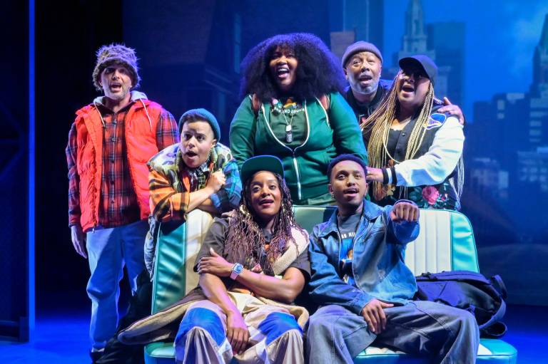 seven colorfully dressed people singing on stage