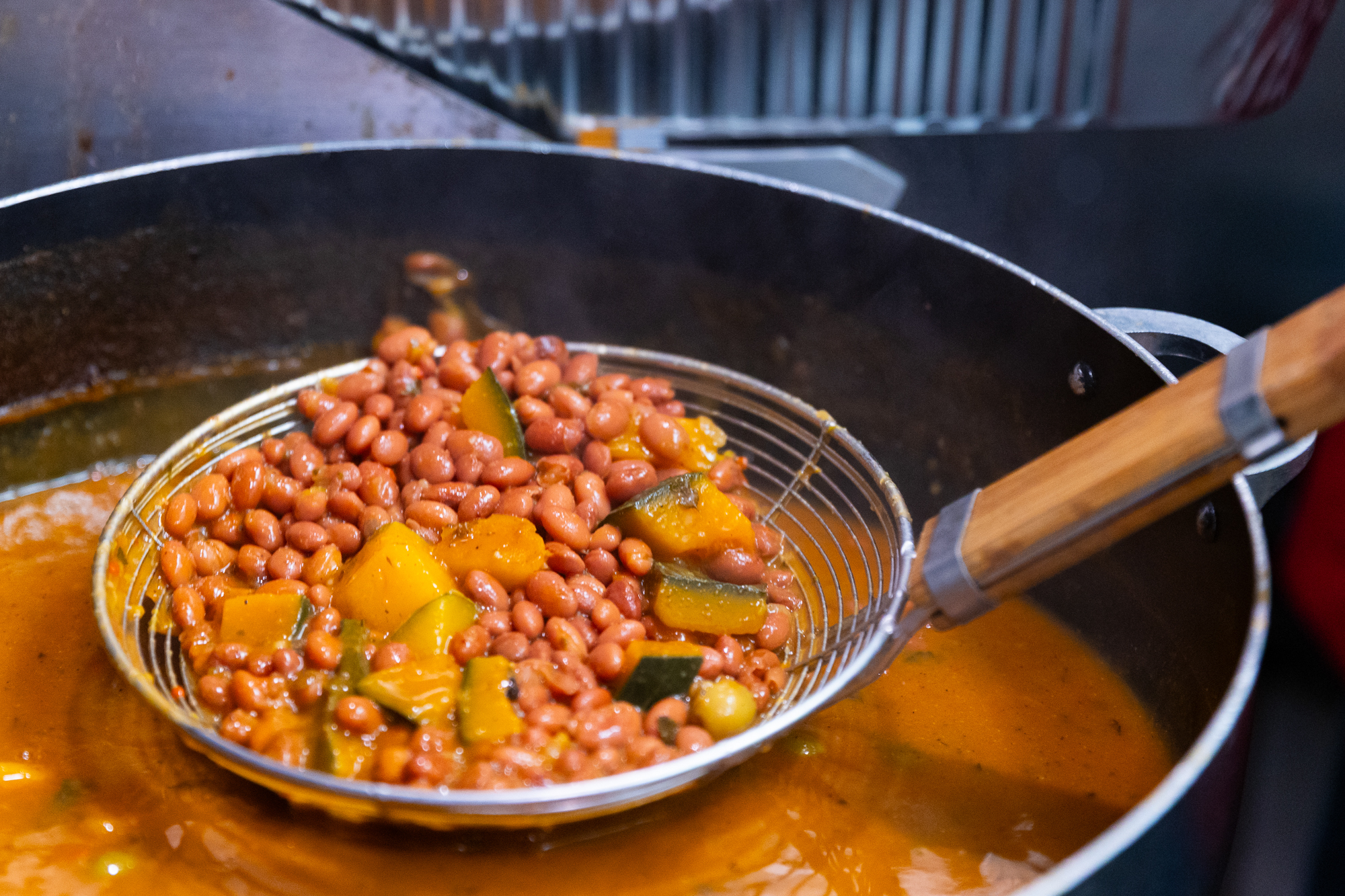 Pink beans strained in a colander held over a large pot.