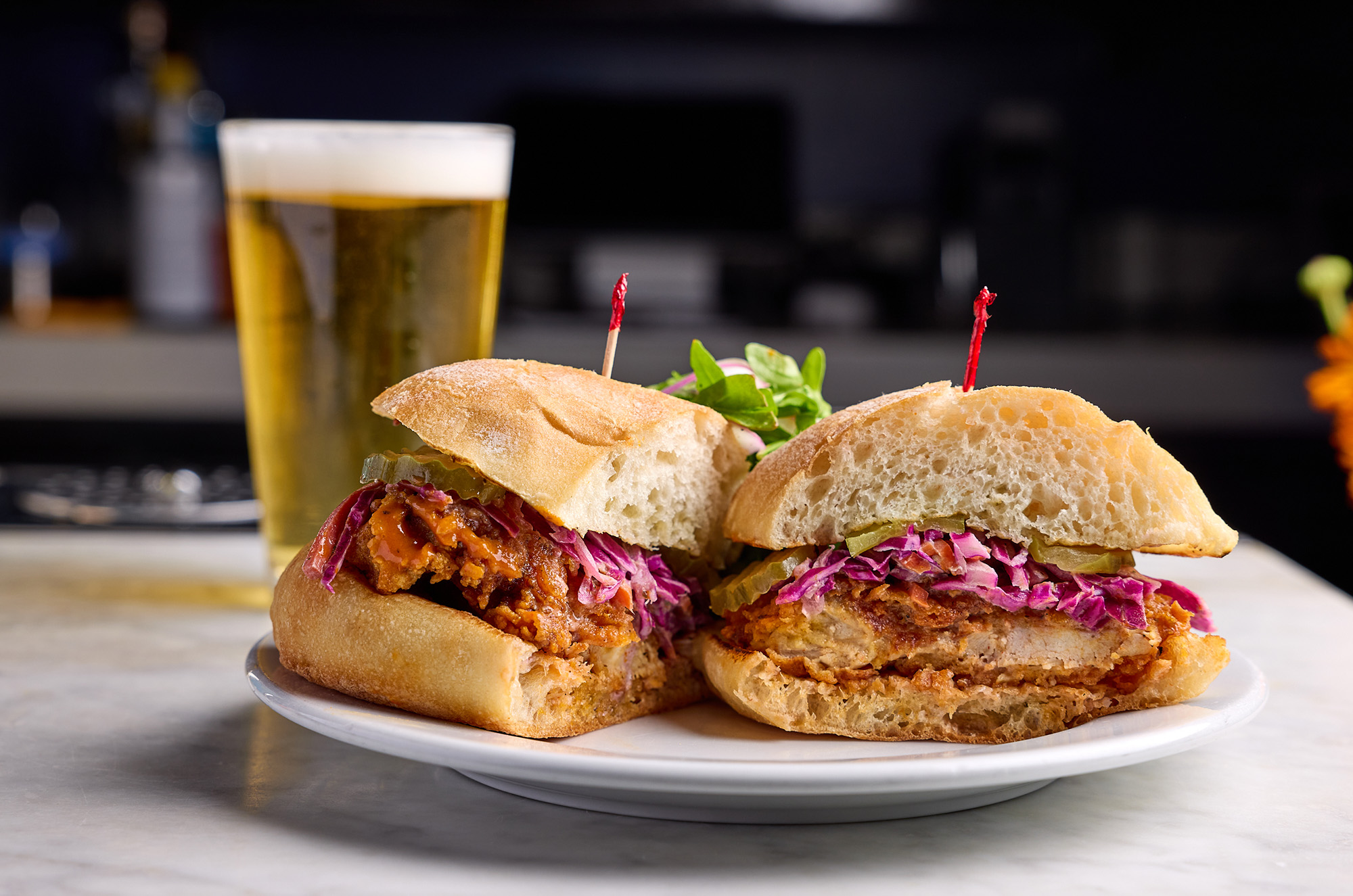 Fried chicken sandwich with purple cabbage topping on a plate. 