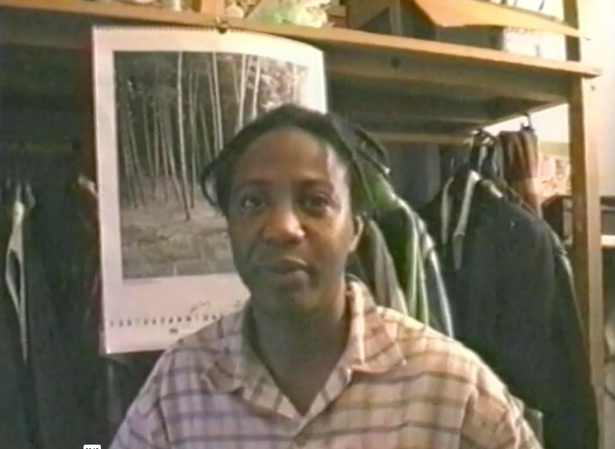 Black person in plaid shirt in front of closet