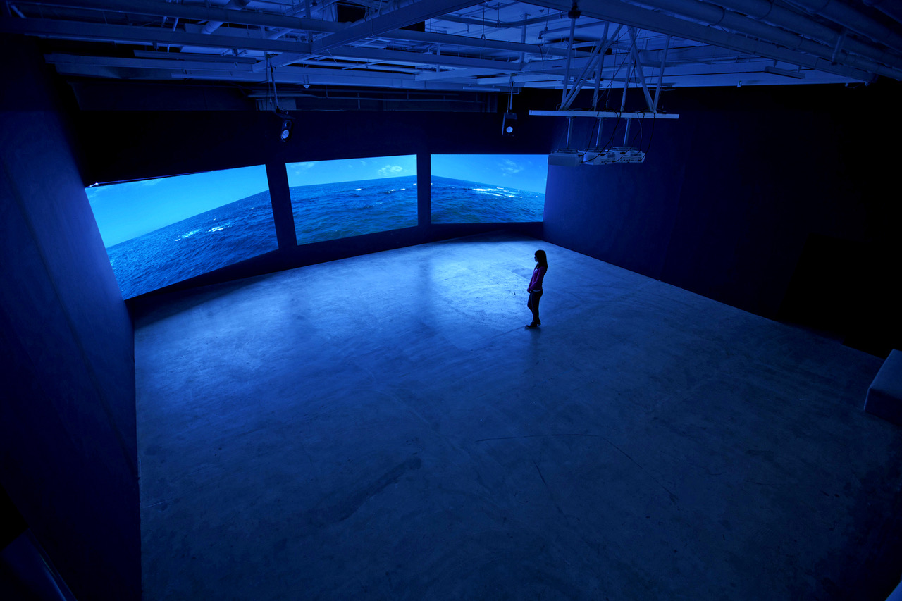 blue-lite three screen projection with one person watching