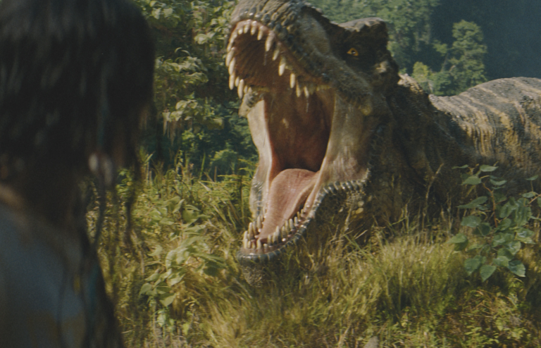 The back of someone's head is visible as they turn to look at a giant, roaring dinosaur in the distance.