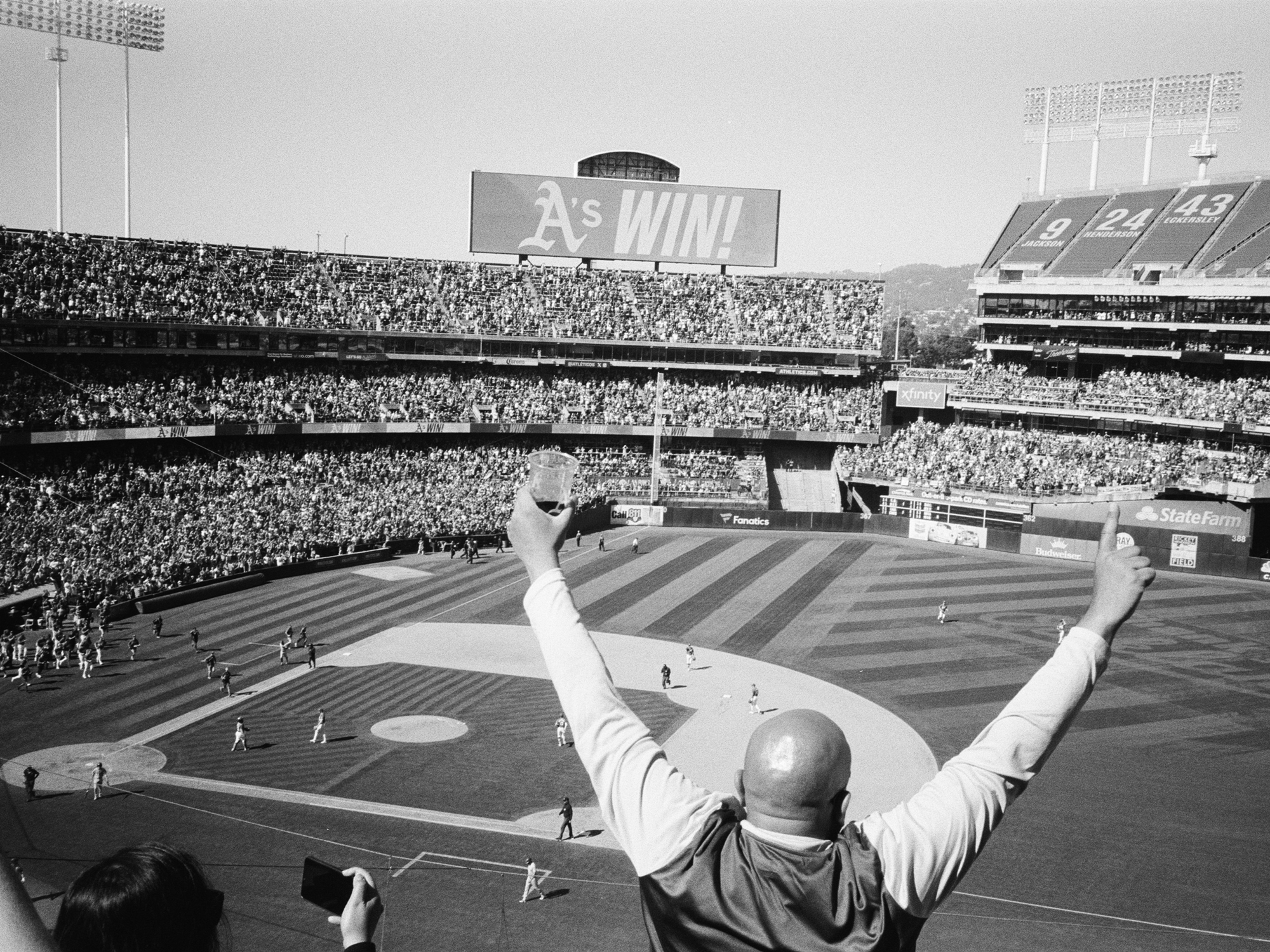 person with arms raised looking down on baseball field