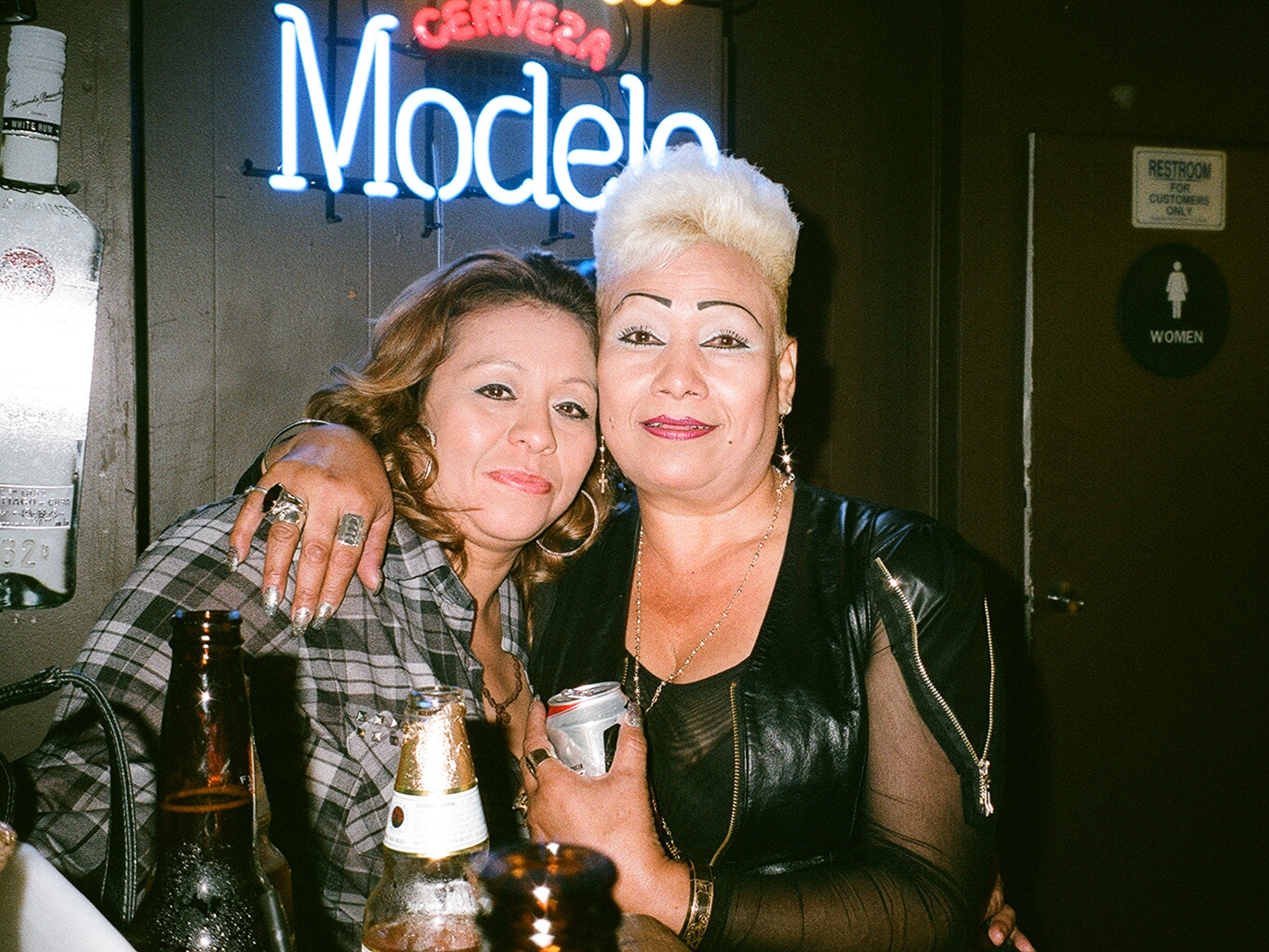 two women pose with drinks at bar