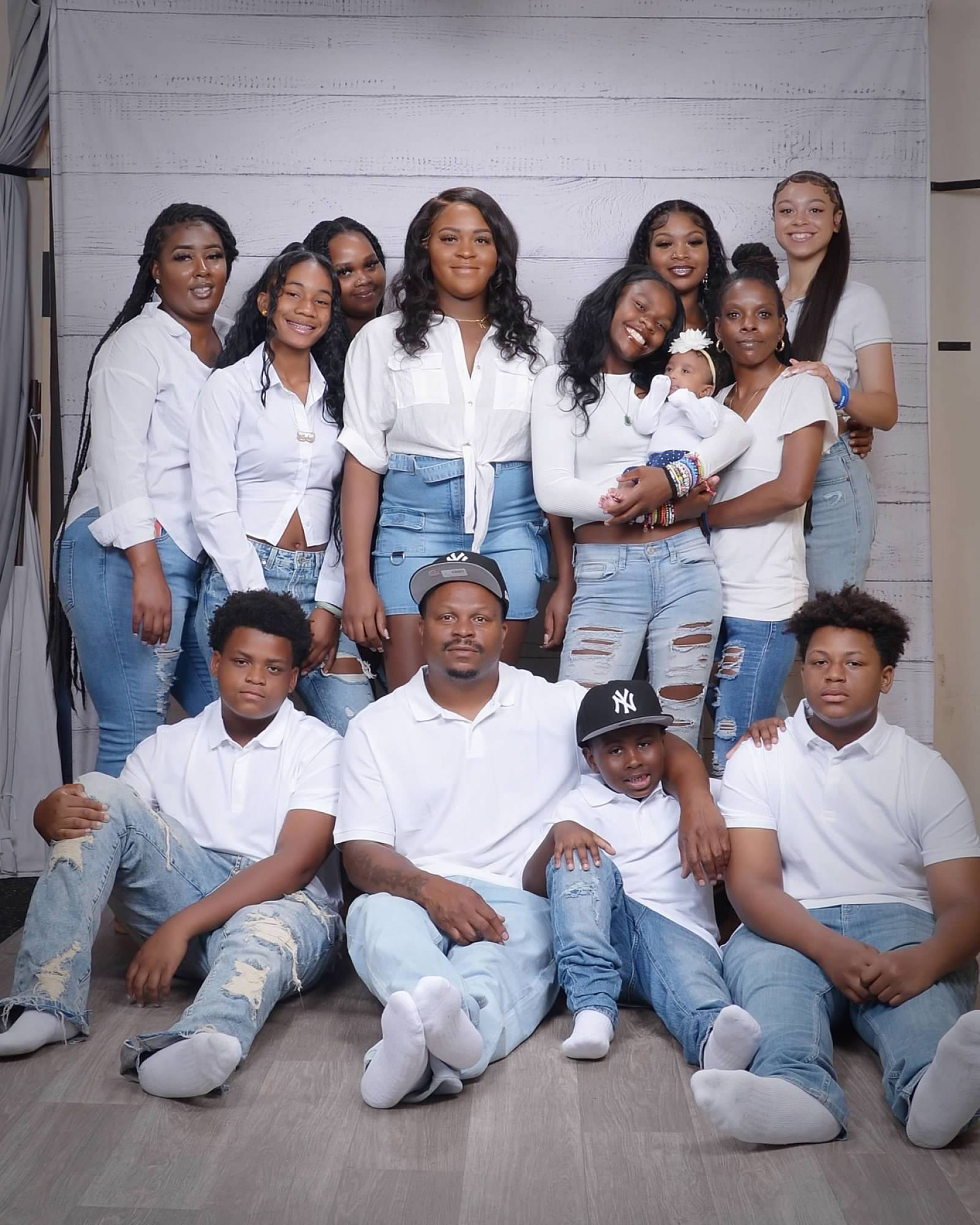 A family in matching outfits (white shirts and faded jeans) poses for a group portrait.