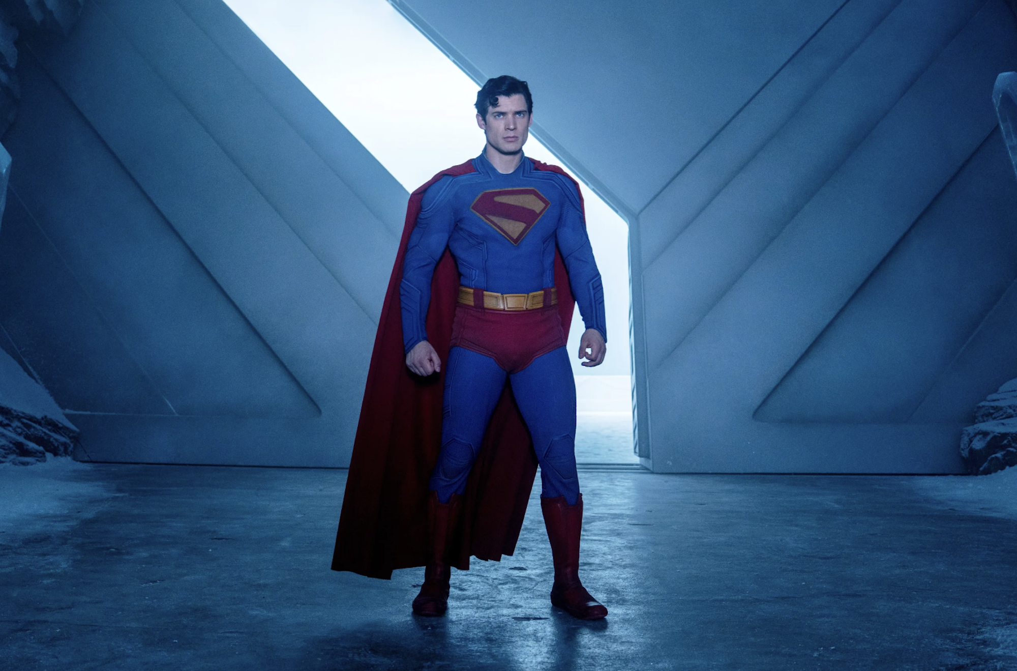 Superman stands firm in a bold stance inside an industrial-looking space.
