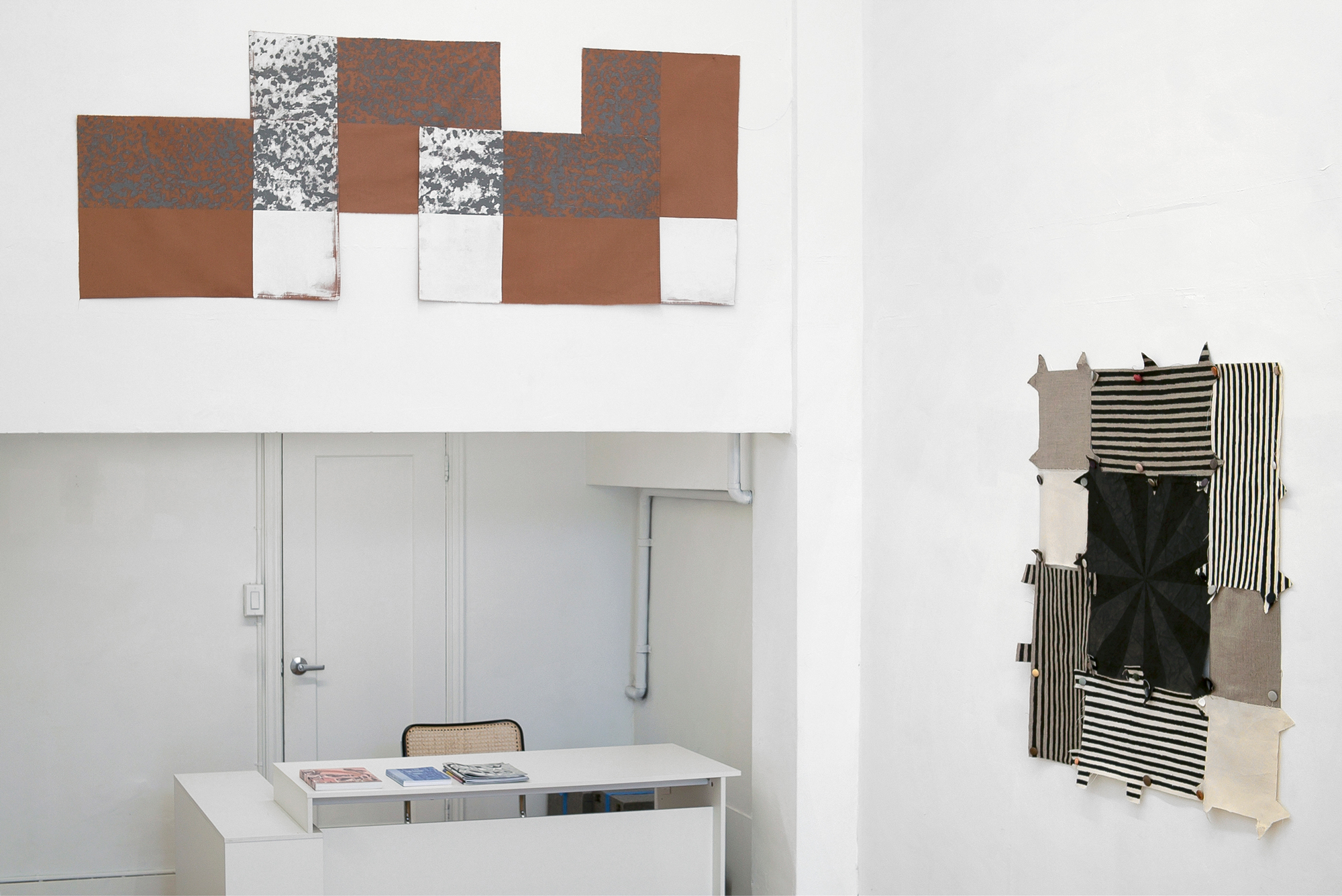 corner of gallery with horizontal tan and white piece over desk, square striped piece at right