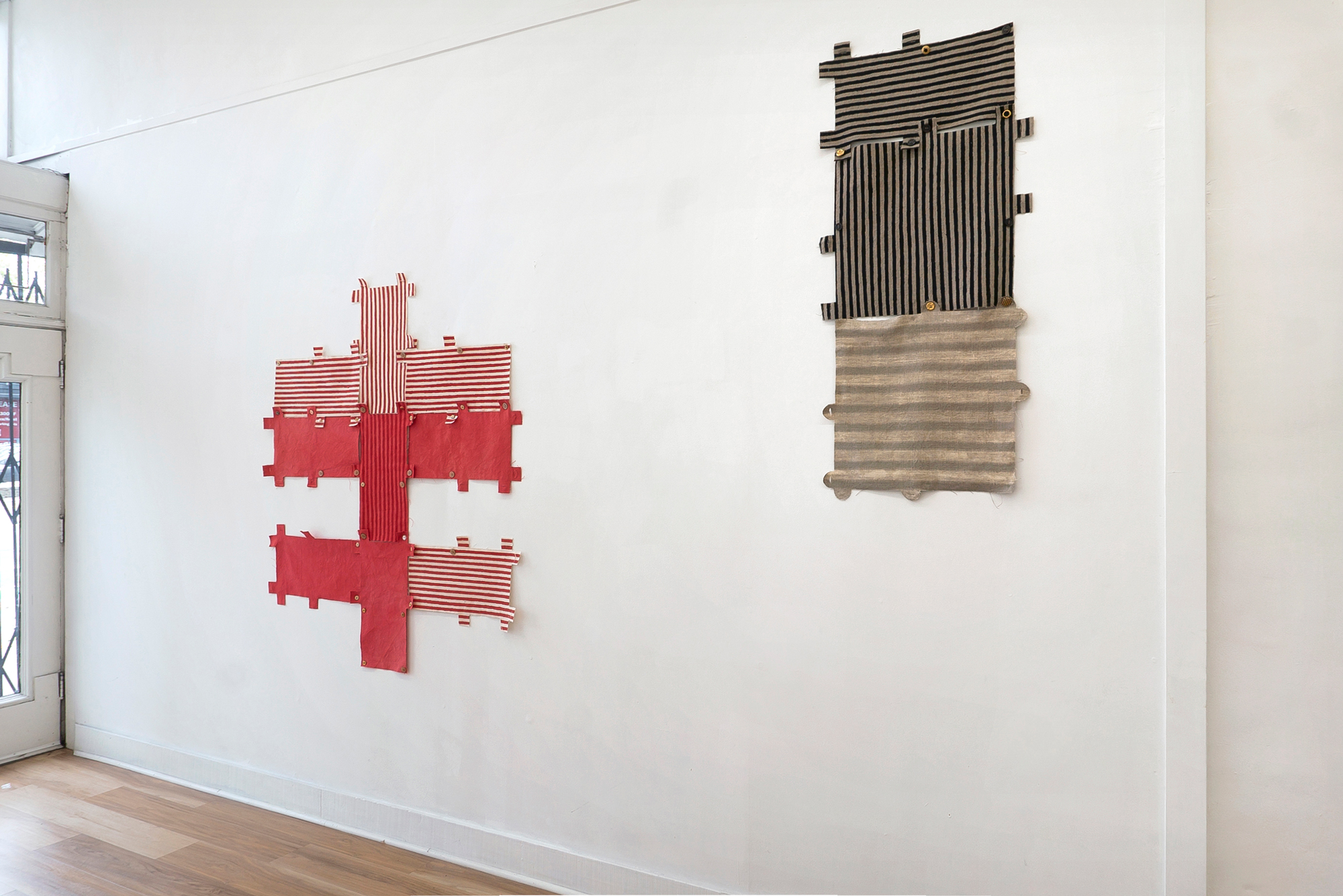 red and white striped shaped textile piece and vertical dark gray striped rectangle on wall
