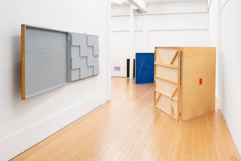 gallery with folding wooden sculptures on wall and floor