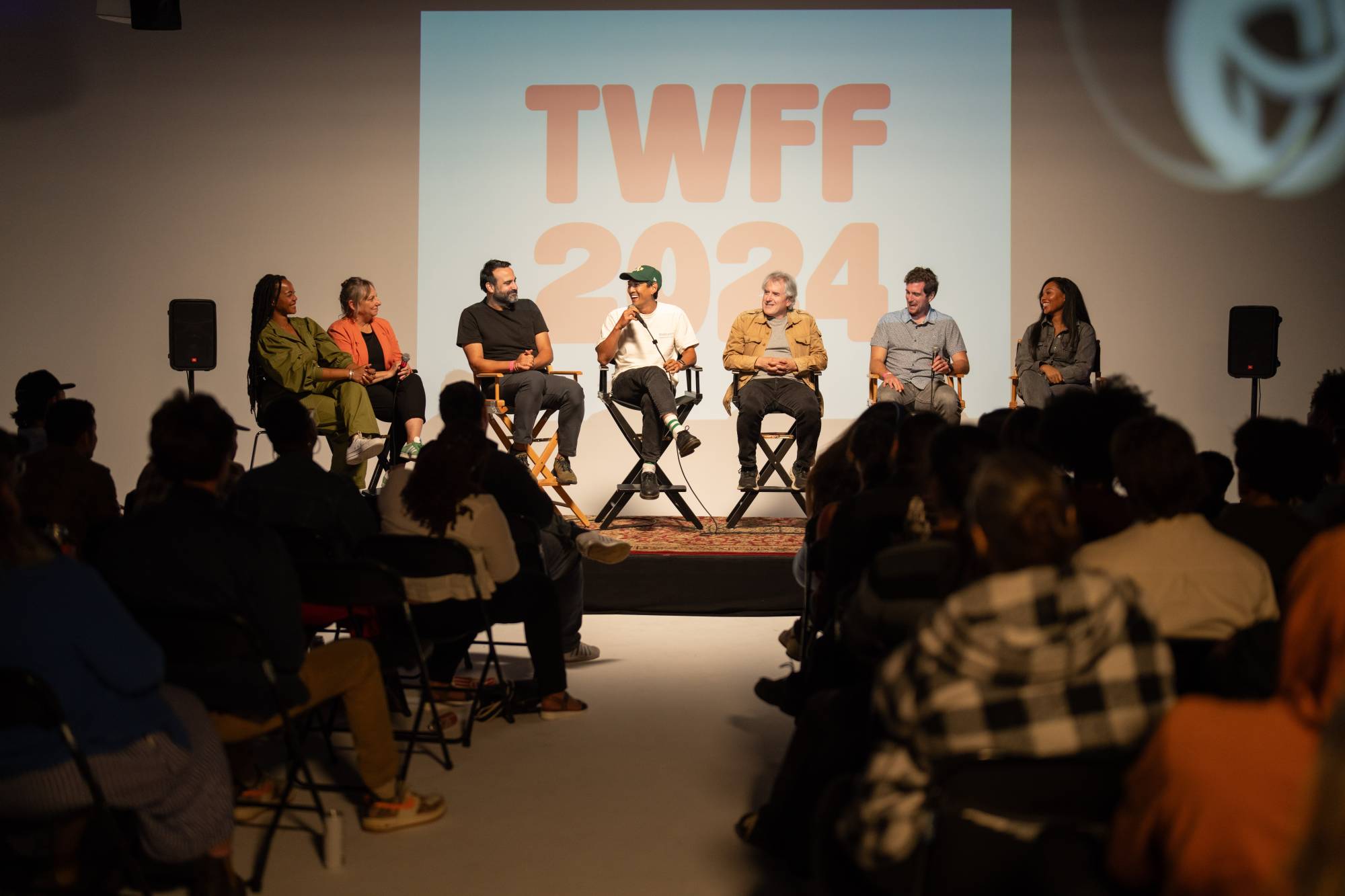 People sitting on a panel in front of a captive audience. Behind the panel are the letters TWFF on a screen, an acronym for The Worst Film Fest.