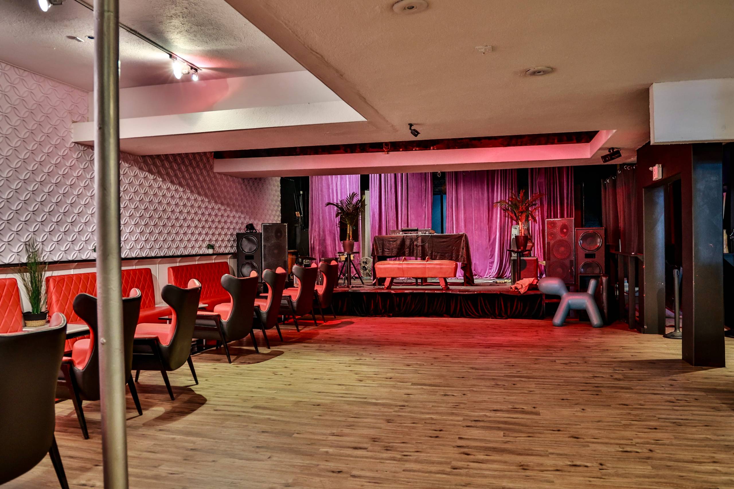 A 2-foot high stage sits at the end of a room that's adorned with plush furniture in pastel pinks and oranges.