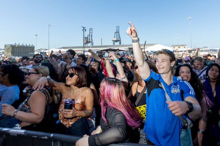 large crowd cheers, shipping cranes in background